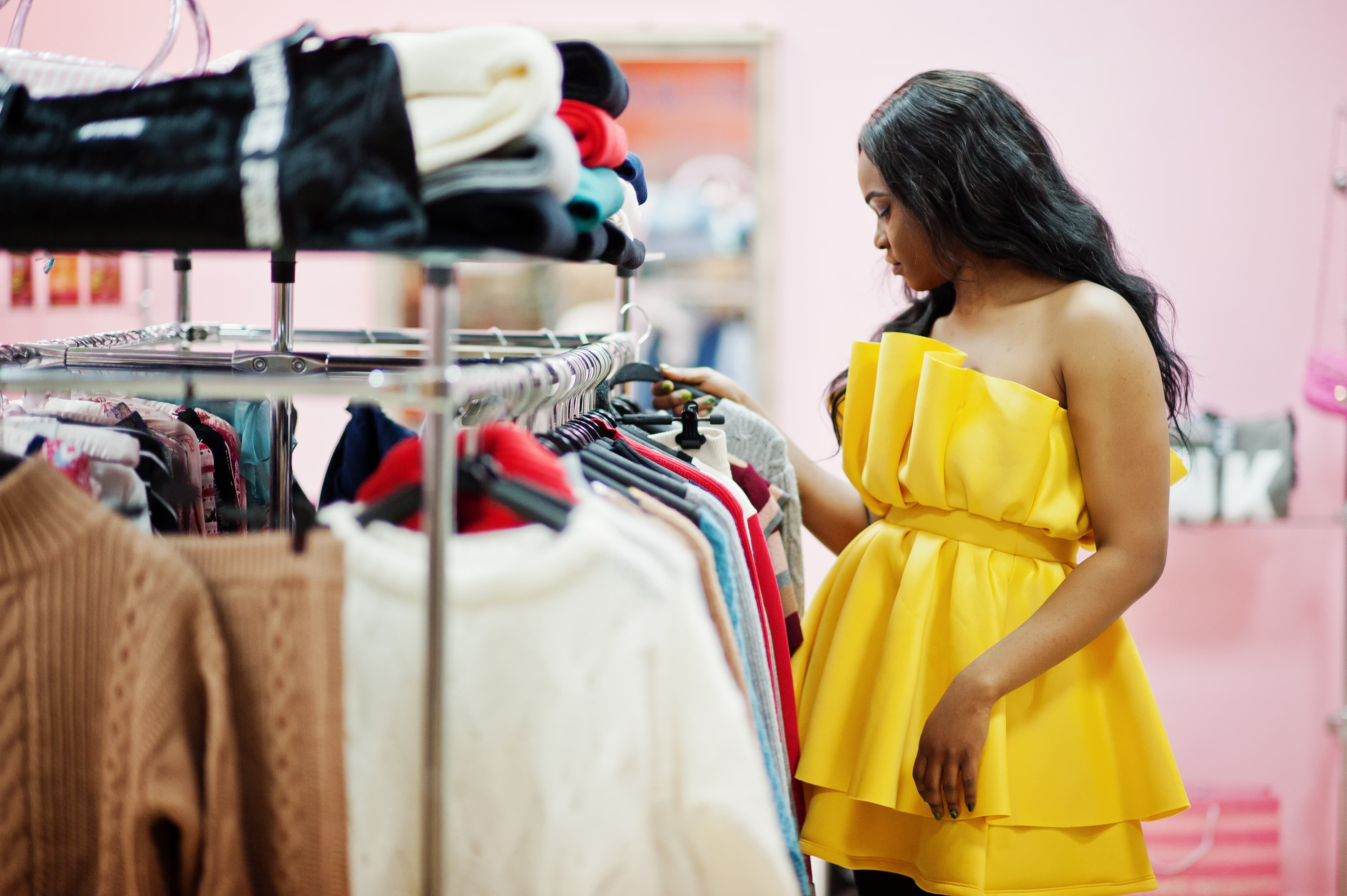 Femme en robe jaune choisissant des vêtements en boutique